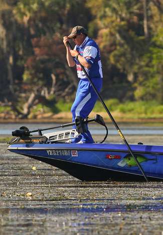 Alton Jones strains to push his boat, while constantly looking for bedding fish.