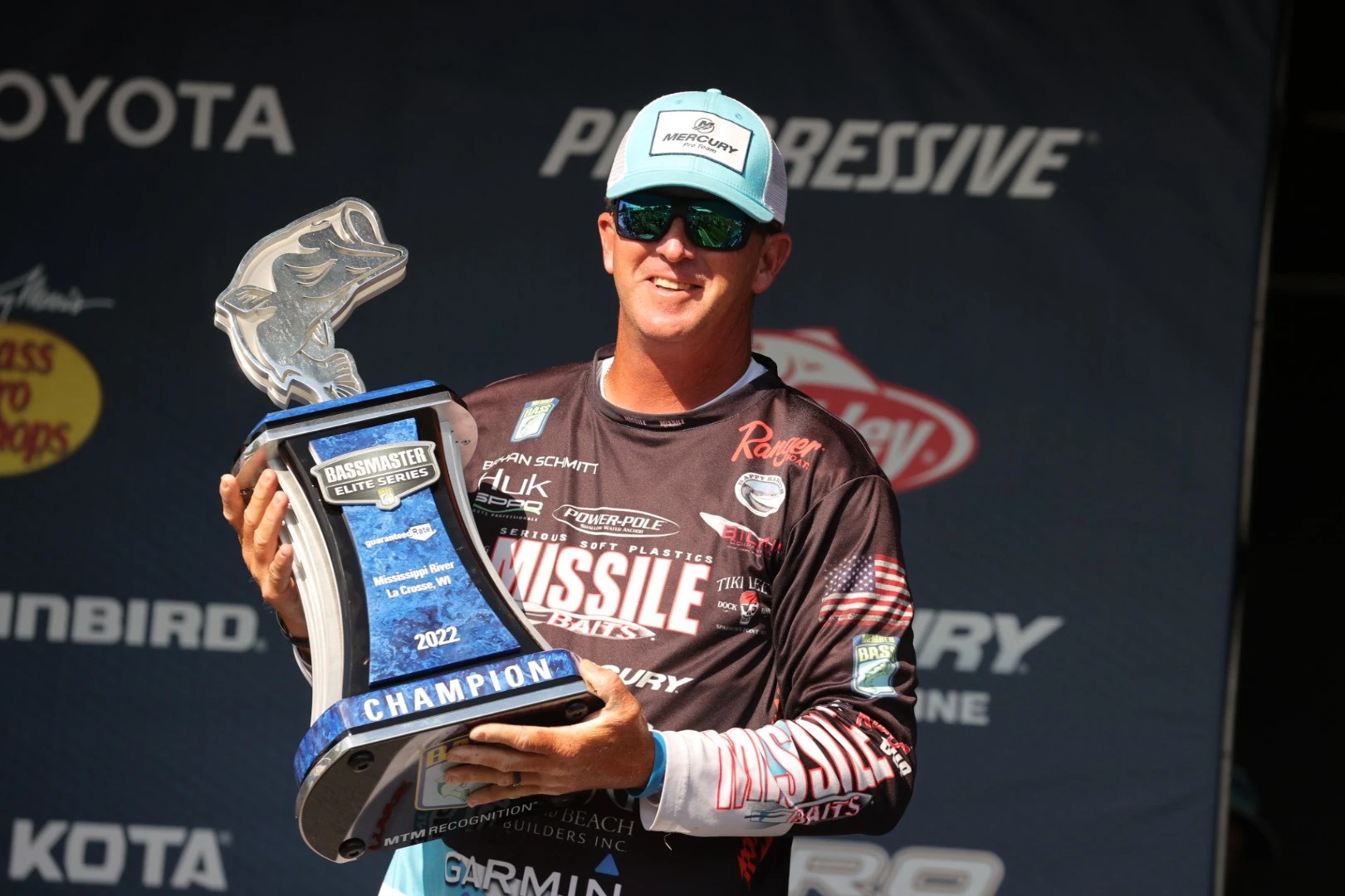 Bryan Schmitt holds a Bassmaster Elite Series trophy on the weigh-in stage